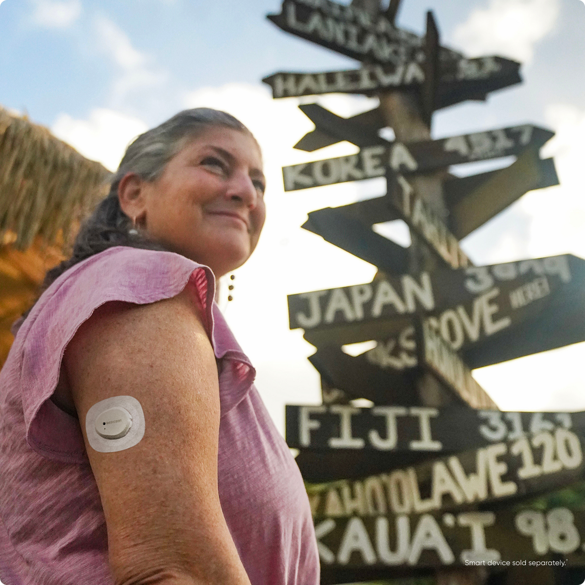 Woman standing in front of large multi-street sign wearing Dexcom sensor